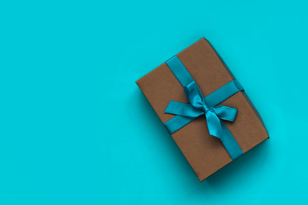 A nice gift box decorated craft papper with a bow on blue background. New Year, Christmas, birthday, Valentines Day, World Womans Day, Fathers Dayの写真素材