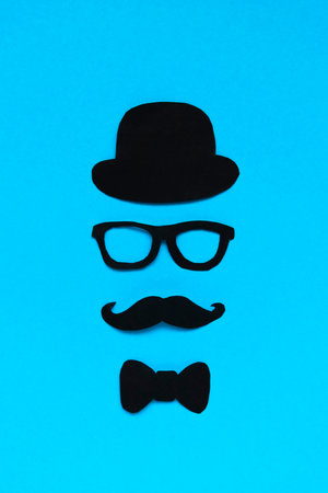Happy Fathers Day concept. Composition of paper decor hat, glasses, bow tie and mustache on blue backgroundの写真素材