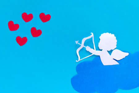 valentines day consept. red hearts and cupid aiming in heart on blue background. creative valentine's day card. flat layの写真素材