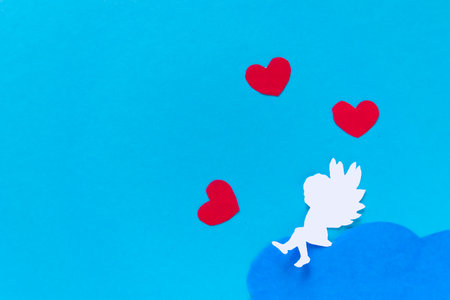 valentines day consept. red hearts and cupid aiming in heart on blue background. creative valentine's day card. flat layの写真素材