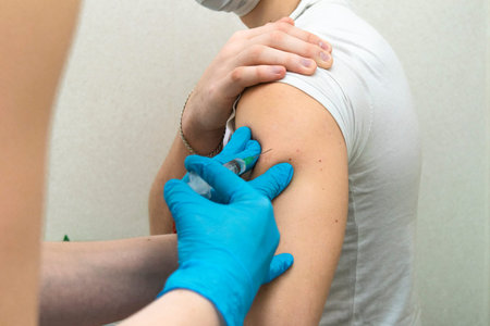 Vaccination concept. Female doctor vaccinating young man in hand. Caucasian peopleの写真素材