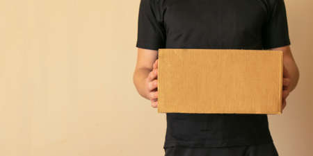 banner delivery man in black clothes hold a cardboard box. copy spaceの写真素材