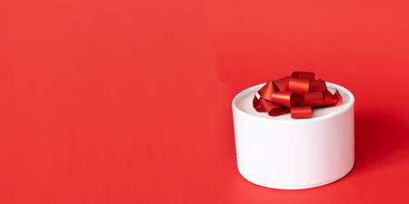 white gift box with red ribbon bow on red background. present for Christmas, new year, valentine dayの写真素材