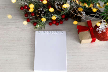 notepad on wooden background with gift and ckristmas light and decoration, space for textの写真素材