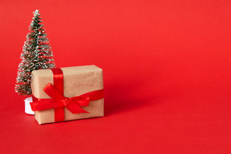 gift box with red ribbon bow and fir tree on red background. present for Christmas, new year,...