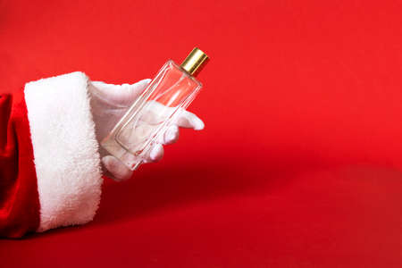 white cream bottle in santa hand on red background. present for Christmas, new year, copy spaceの写真素材