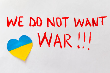 The concept of ending the war in Ukraine. Broken heart in the colors of the flag of Ukraine and Russia in female hands with text we do not want warの写真素材