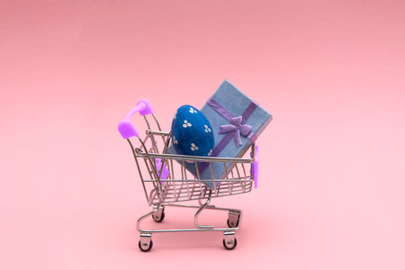 Easter eggs colorful in the shopping cart on pink background. Copy space for Text.