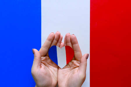 Paper heart in the colors of the flag of France in female hands on color backgroundの写真素材