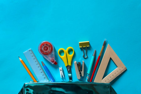 Stationary, back to school,creativity and education concept. Notebook, pen, pencil, eraser, ruler, paper clips, stapler and brush on blue background, flat layの写真素材