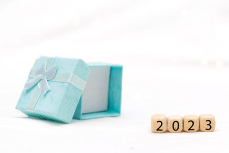 Decorative blue gift box on white background with bokeh of lights and numbers of year 2023