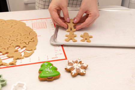 Caucasain woman rolls out the dough with a rolling pin and cuts cookies with cookie cutters at the...