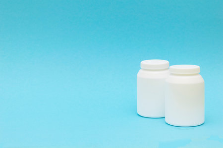 two pill bottle, medicine container for vitamins on blue background.の写真素材