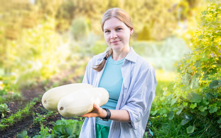 Caucasian girl holding zucchini in her hands. Harvest fresh raw vegetablesの写真素材