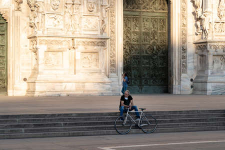 Milan, Italy - May 4, 2020: Bicyclist sitting on Duomo square. Italy enters second phase of coronavirus lockdown. People allowed exercise outdoor wearing face mask and maintaining social distancingのeditorial素材