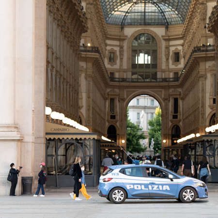Milan, Italy - May 4, 2020: People walk in historic center of Milan. Police car keeps order. Second phase of coronavirus lockdown. People outdoor wearing face mask and maintaining social distancingのeditorial素材