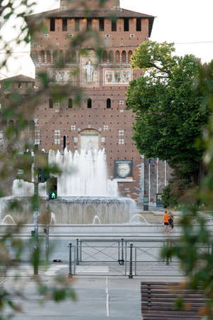 Milan, Italy - May 4, 2020: people walking outdoor, sitting near Sforza Castle fountain wearing face mask. On May 4th Italy eases coronavirus movement restrictions after two month lockdown, phase 2のeditorial素材