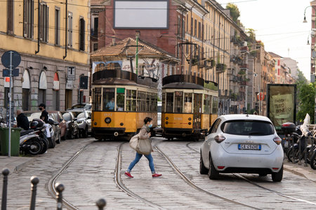 Milan, Italy - May 8, 2020: Woman in protective mask walks across the street in Naviglio Grande...