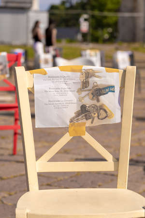 Milan, Italy - May 8, 2020. Restaurant strike against reopening at half capacity. Sign banner on chair with restaurant name. Difficulties of reopening after coronavirus covid-19 lockdownのeditorial素材