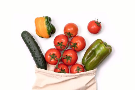 Summer vegetables in reusable eco friendly cotton bag on white. Zero waste, plastic free shopping, ecological concept. Sustainable lifestyle. Vegetable grocery from local farmers market in textile bagの写真素材