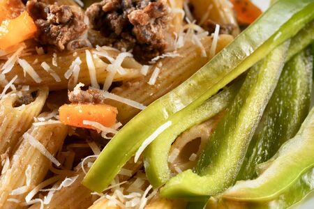 Delicious gourmet pasta with meat and fresh salad. Macaroni with green bell pepper. Italian cuisine. Colorful food concept. Macro, close upの写真素材