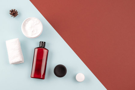 Skin care products on brown and blue surface. Frame from shampoo or cosmetic lotion bottle, towel,...
