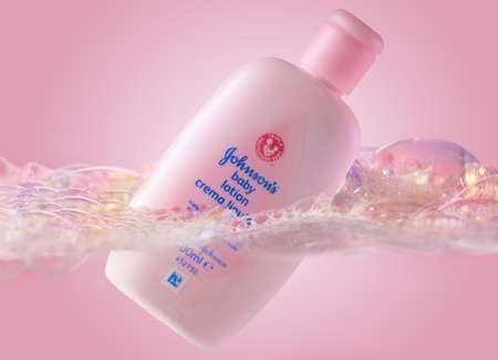 Pink Johnsons baby lotion swimming in foamy water. Skin care moisturizing product in plastic bottle. Baby skincare product on pink backdrop. Studio shotのeditorial素材