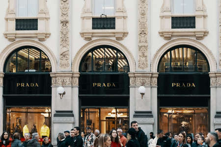 Prada logo and exterior of luxury fashion shop in Milans Fashion District, Montenapoleone area. People passing by the store. Prada is an Italian luxury fashion house Milan, Italy - 31.10.2019.のeditorial素材