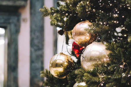 Festive outdoor decorative christmas lights background. Christmas tree branch decorated with baubles, balls on architectural landmark background. Holiday decorations on tree with blurred backdrop.の写真素材