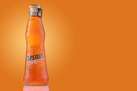 Bottle of Aperol Spritz summer cocktail drink on orange background.