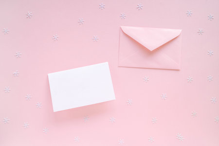 Blank Christmas Card and pink envelope with Christmas decorations on pink surface, top view. Holiday...
