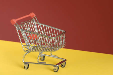 Empty shopping cart on colorful yellow and brown background. Online shopping or e-commmerce concept. Copy space, banner.の写真素材