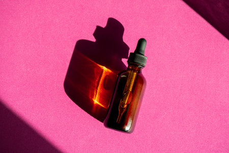 Anti aging serum with collagen and peptides on purple surface in brown glass bottle with shadows. Hyaluronic acid oil mockup in brown bottle. Sunlight and shadow from cbd oil bottle.の写真素材