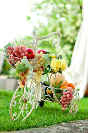 Decorative bicycle with fruit in basket on grass on green summer background.の写真素材
