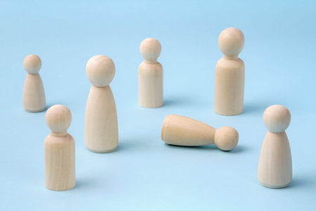 People gathering together to help person feeling bad or fainting. Person lying on the ground and people standing around. Wooden figurines concept. Medical assistance concept.の写真素材