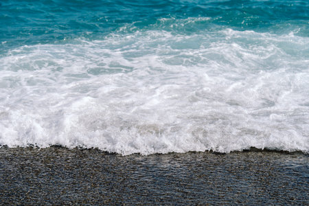White foamy waves on sandy beach closeup. Seaside on sunny summer day. Summer vacation time concept.