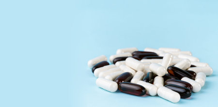 Pharmaceutical pills and vitamins. Medicine or supplement capsules on blue surface. Probiotic,...
