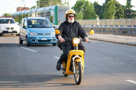 Man riding motorbike in busy city street traffic. Motorcyclist drives moped on the road. Milan, Italy - May 26, 2020のeditorial素材