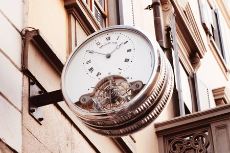 Vintage street clock with roman numerals hanging on the wall of building in center of european city....
