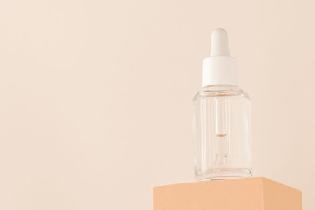 Hyaluronic acid, serum skincare glass bottle on beige podium pedestal, low angle view. Serum product...