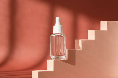 Serum skincare glass bottle, hyaluronic acid on brown podium pedestal, art deco. Serum product cosmetic with peptide and collagen. Modern brand cosmetics packaging. Cosmetic showcase, art decoの写真素材