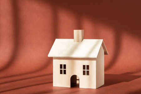 Wooden house building miniature model with shadow on brown background. Home, sweet home. Buying new apartment, mortgage, rent, business real estate insurance concept. New property, family lifeの写真素材