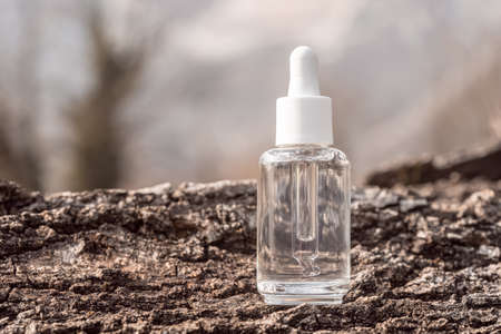 Cosmetic serum bottle mockup on tree bark background. Anti aging product, luxury body care and organic science concept. Moisturizing beauty skincare cosmetics packaging with natural ingredientsの写真素材