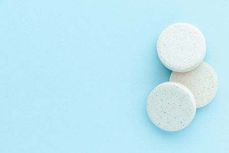 Heap of medicine pills on blue surface, isolated, top view. Circle round medical tablets,...