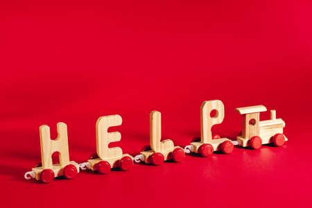 delivery concept. Wooden train made of letters Help on red backdrop. Humanitarian aid, shipping .の写真素材