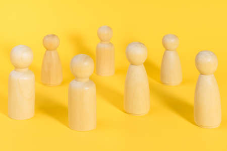 Wooden people figures stand on yellow backdrop, relationship, communication problems between people. Business, teamwork metaphor. Society behavior, social distancing during pandemicの写真素材