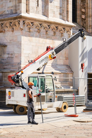 Milan, Italy - July 7, 2020. Construction worker on duty standing close to crane. Duomo cathedral...