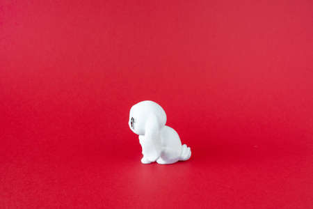 White puppy toy on red background. Minimalist concept, front view, bannerの写真素材