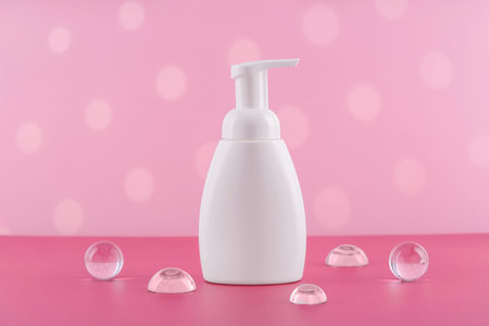 Bath soap white cosmetic bottle mockup on pink background with stylish props. Body care foam product...