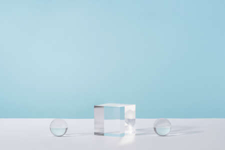 Pedestal cosmetic display glass podium platform with stylish props for product presentation, cosmetics geometric stand, mockup scene for jewellery mock up. Acrylic blocks and balls on blue backgroundの写真素材